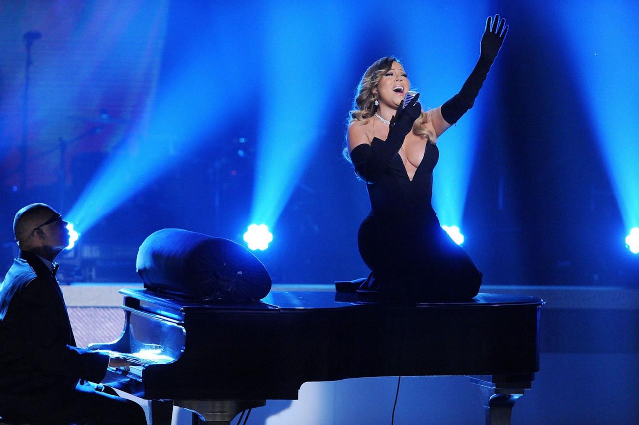 Mariah Carey gorgheggia sul piano, mani in aria