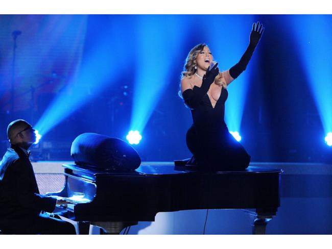 Mariah Carey gorgheggia sul piano, mani in aria