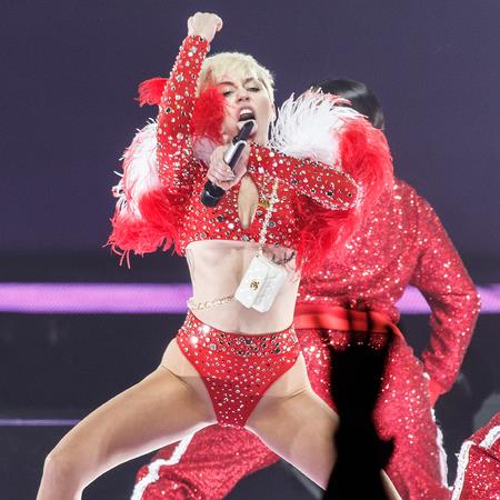 Miley con un vestitino rosso luccicante e una pelliccia sulle spalle