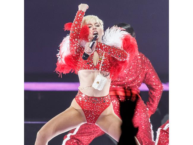 Miley con un vestitino rosso luccicante e una pelliccia sulle spalle