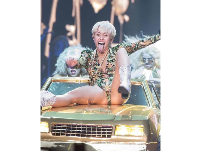 Miley Cyrus a gambe larghe e lingua fuori durante una performanca