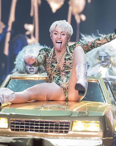 Miley Cyrus a gambe larghe e lingua fuori durante una performanca