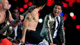 Bruno Mars sembra volare e, con la bocca spalancata, guarda qualcuno: cameraman o una ragazza del pubblico?