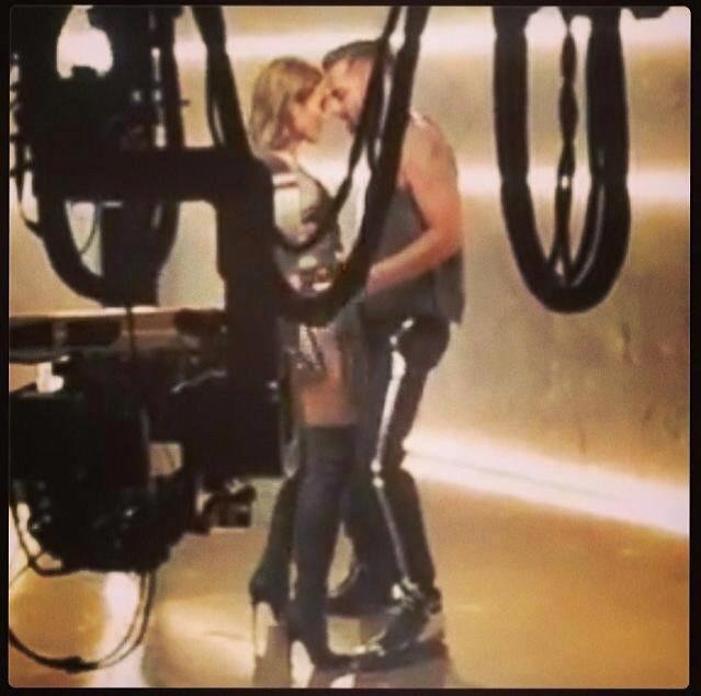 Jennifer Lopez e Ricky Martin cantano molto vicini in una stanza illuminata da neon.