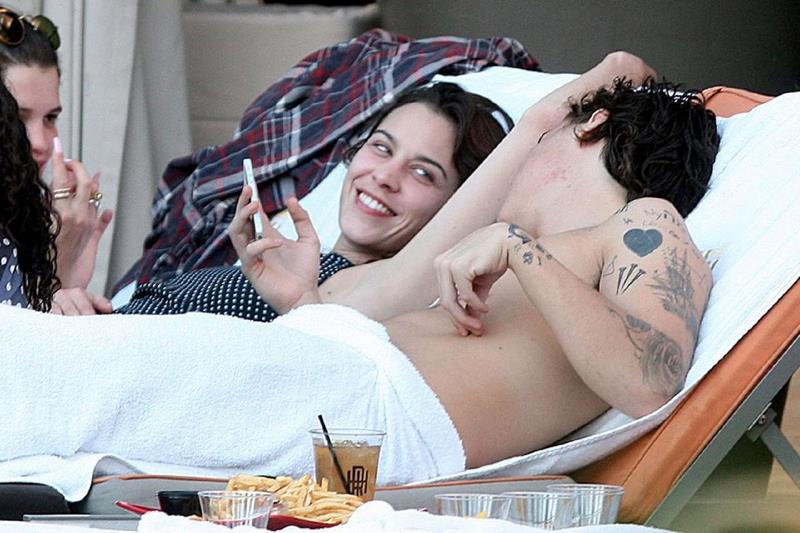 Harry Styles controlla il cellulare mentre si rilassa su di una sdraio.