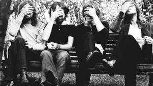 Pink Floyd che si coprono gli occhi seduti insieme su una panchina 