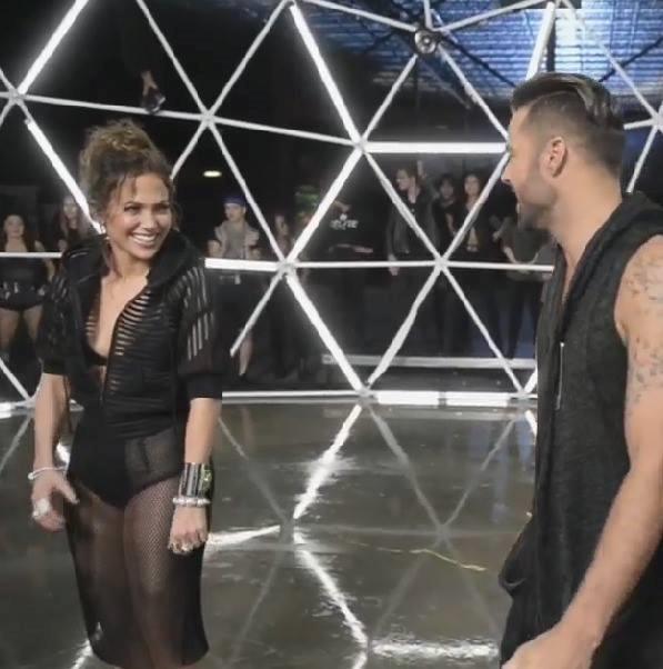 Jennifer Lopez e Ricky Martin si sorridono in una gabbia fatta di neon