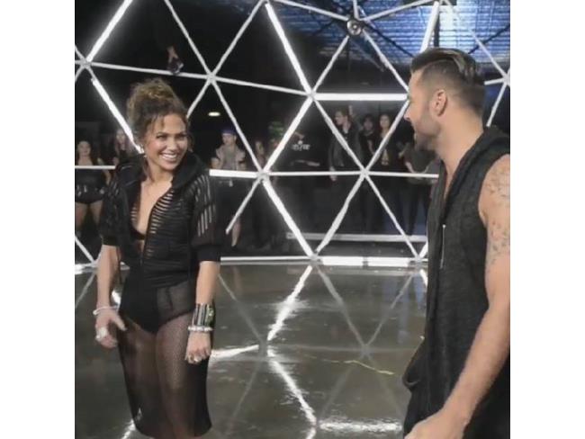Jennifer Lopez e Ricky Martin si sorridono in una gabbia fatta di neon