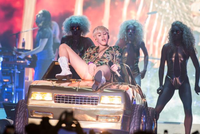 La Cyrus adagiata su una macchina si tocca i genitali