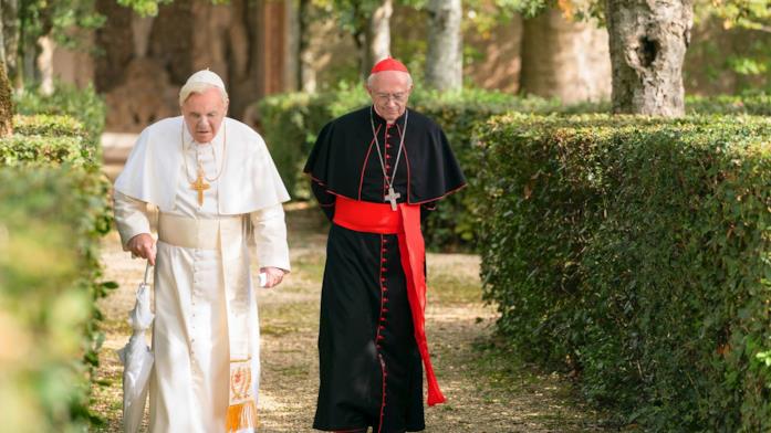 Jonathan Pryce e Anthony Hopkins nei panni di Papa Francesco e Papa Benedetto XVI nel film Netflix Papa Benedetto XVI e Jorge Mario Bergoglio camminano in un giardino