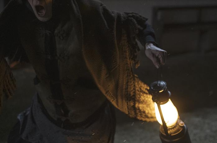 Una donna con una lampada scappa terrorizzata da un fantasma