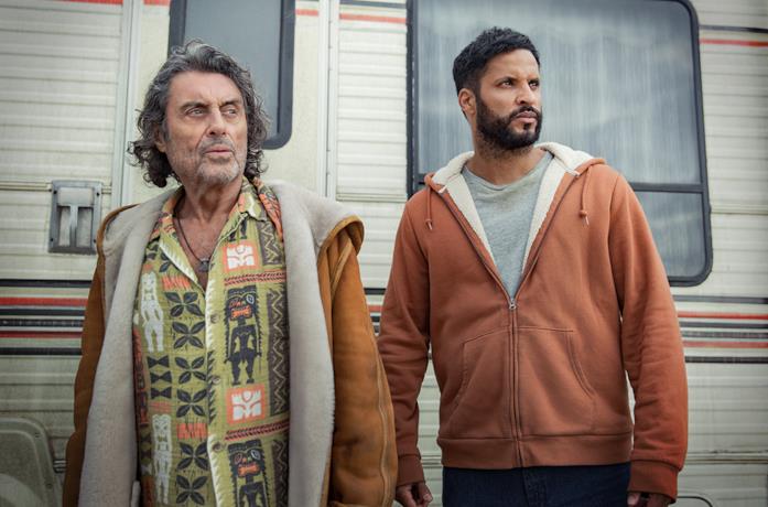 Ian McShane e Ricky Whittle davanti a una roulotte