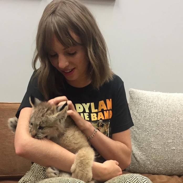 Maya Hawke nel 2019, con un leoncino Maya Hawke seduta su un divano con un in braccio un leoncino