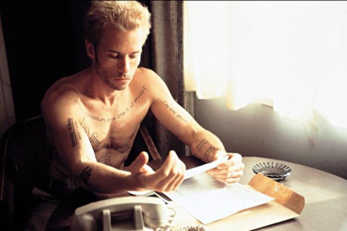 Guy Pearce biondo e con il corpo coperto di tatuaggi in una scena del film