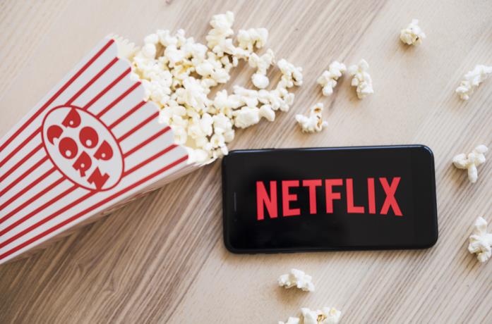 Il logo di Netflix sul display di uno smartphone, a sinistra dei pop corn