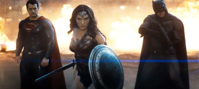 Wonder Woman si frappone fra Superman e Batman per affrontare il mostro Doomsday Henry Cavill, Gal Gadot e Ben Affleck nei loro costumi di scena, in posa da battaglia su sfondo infuocato