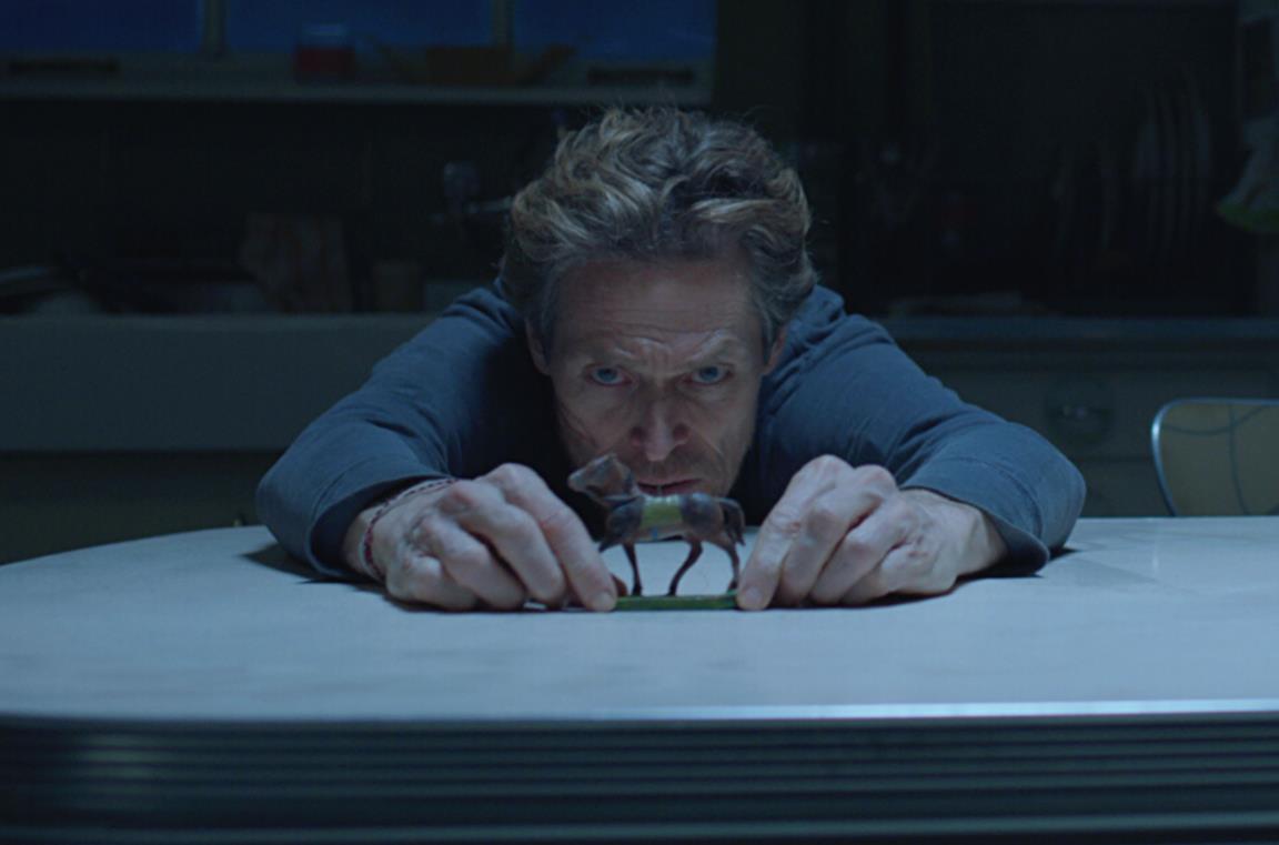 Willem Dafoe osserva un cavallino giocattolo