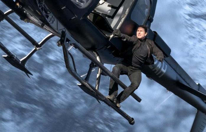 Tom Cruise aggrappato ad un elicottero in una foto del film