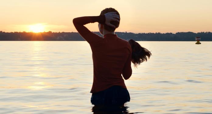 Lo spoglio dello sheitel in Unorthodox Esty (Shira Haas) si toglie lo sheitel mentre si immerge nel lago a Berlino