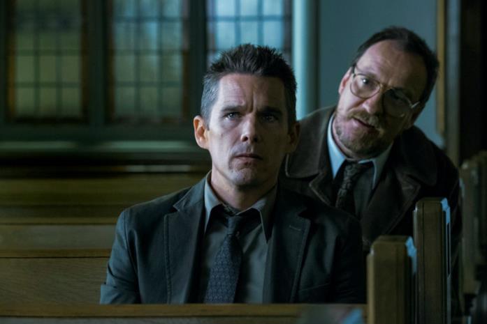Ethan Hawke e David Thewlis in Regression Lo psicologo Raines e il detective Bruce discutono seduti sulle panche della chiesa