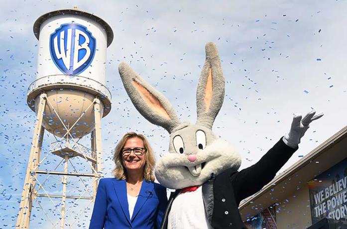 Il CEO di Warner Bros. Ann Sarnoff e Bugs Bunny; alle spalle il nuovo logo aziendale