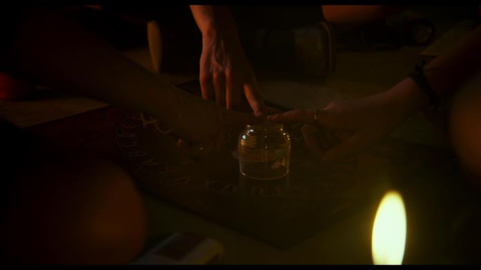 Una scena della seduta spiritica in Veronica Le mani di Veronica, Rosa e Diana seguono il puntatore della tavoletta Ouija