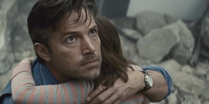 Bruce Wayne/Ben Affleck si sente impotente di fronte alla distruzione causata da Zod e Superman Primo piano di Ben Affleck che abbraccia una bambina, con macerie sullo sfondo