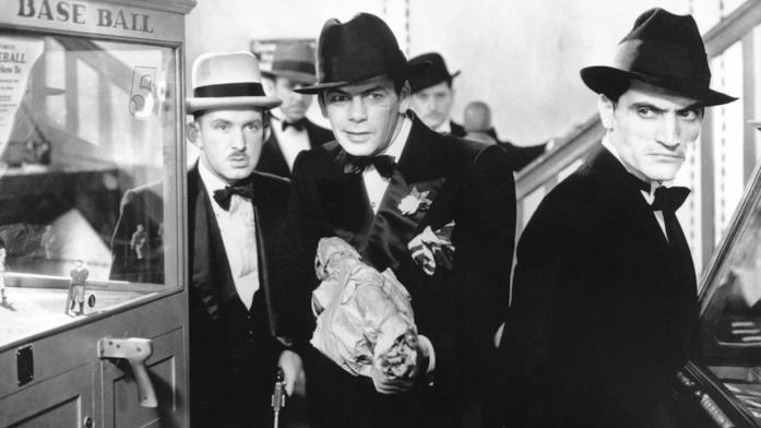 Una scena di Scarface - Lo sfregiato Tony Camonte (Paul Muny) nasconde una pistola in una busta di carta, circondato dai suoi scagnozzi