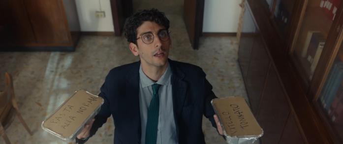 Pietro Castellitto nel film I Predatori Federico (Pietro Castellitto) ha in mano due porzioni di pasta, mentre parla con un uomo