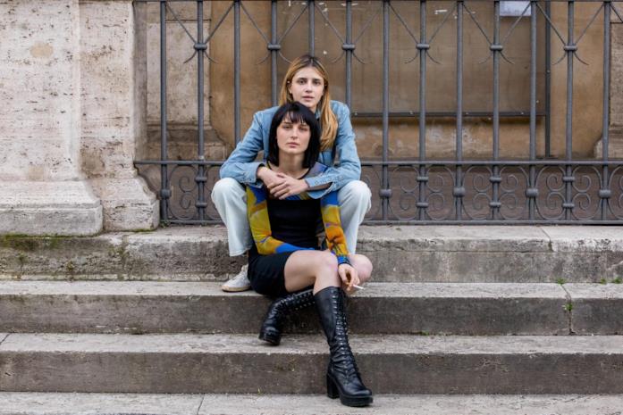 Benedetta Porcaroli (Chiara) e Alice Pagani (Ludovica) nella terza stagione di Baby Chiara e Ludovica si abbracciano mentre sono sedute su degli scalini