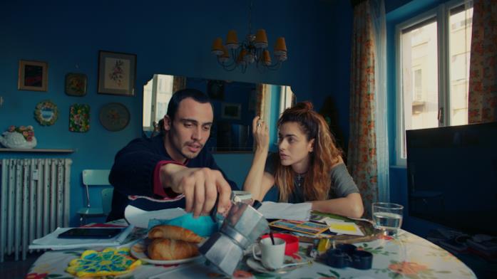 Simone Liberati e Miriam Leone in una scena de L'amore a domicilio Simone Liberati e Miriam Leone seduti a tavola ne L'amore a domicilio