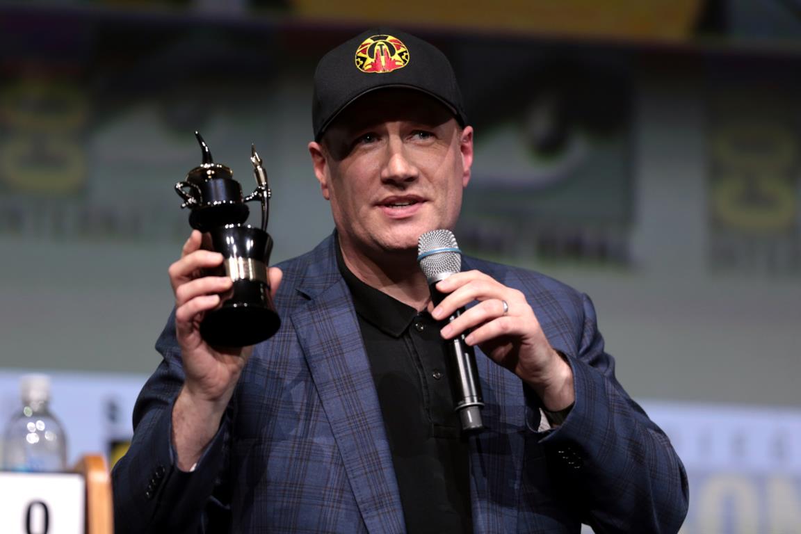 Kevin Feige con un premio in mano e un microfono, mentre parla