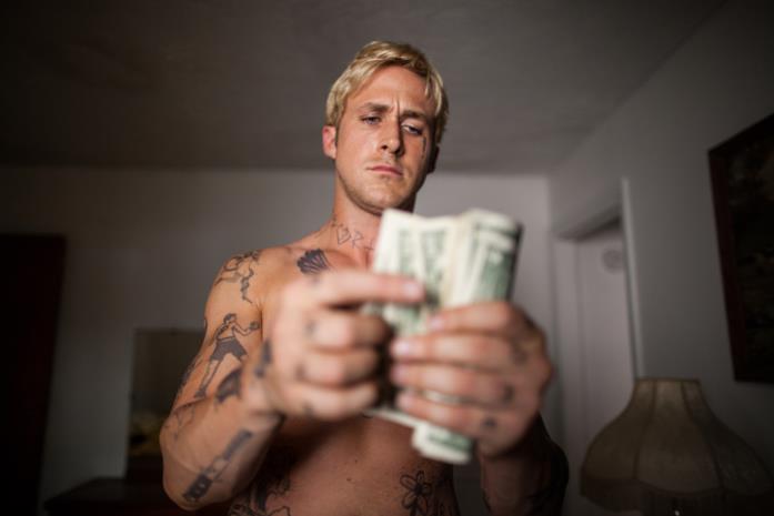 Come un tuono: Ryan Gosling è il primo di una generazione di uomini Ryan Gosling a torso nudo mentre conta i soldi in una scena del film