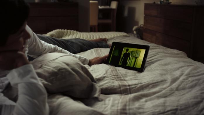 Un ragazzo guarda una serie su un tablet Un ragazzo sdraiato sul letto guarda una serie su un tablet