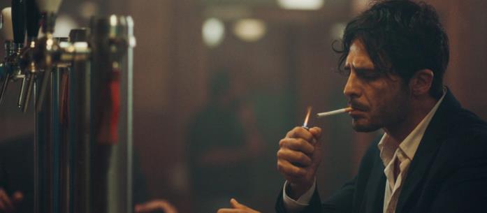 Calibro 9 su Rakuten TV a febbraio Un uomo fuma una sigaretta al bar