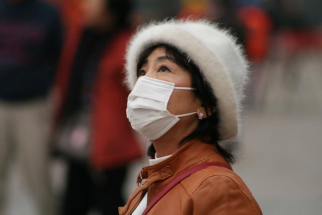 Donna cinese con la mascherina, per proteggersi dallo smog (diminuito grazie al coronavirus)