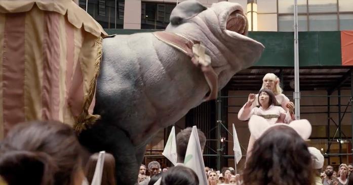 Okja viene trascinato fuori da una tenda tra lo stupore della folla e di Mija Okja esce da un tendone urlando e spaventando il pubblico, la presentatrice e la piccola Mija
