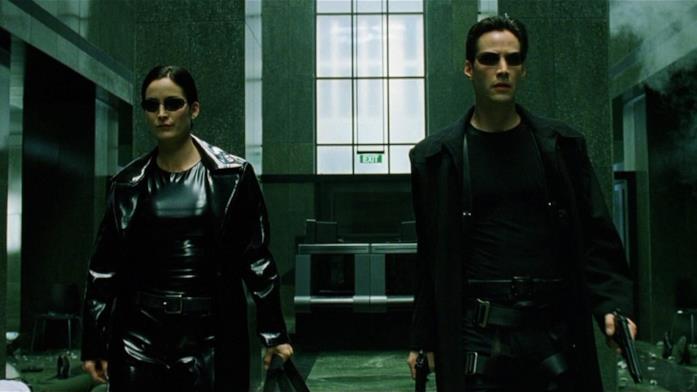 Matrix 4 ferma le riprese Trinity a sinistra e Neo a destra, entrambi con le pistole in mano