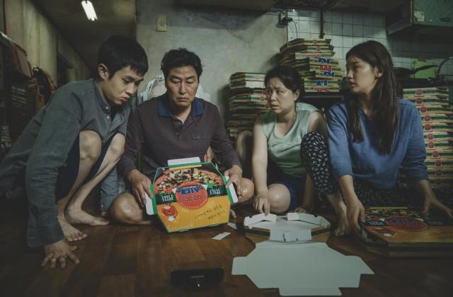 Scena di Parasite La famiglia Kim piega cartoni della pizza per vivere in una scena di Parasite