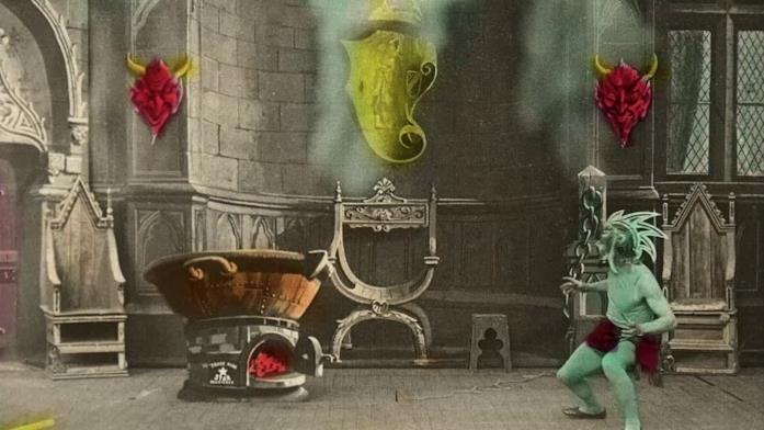 Una scena da Le chaudron infernal Un satanasso guarda un calderone che bolle in una sala antica. La pellicola in bianco e nero è colorata a mano.