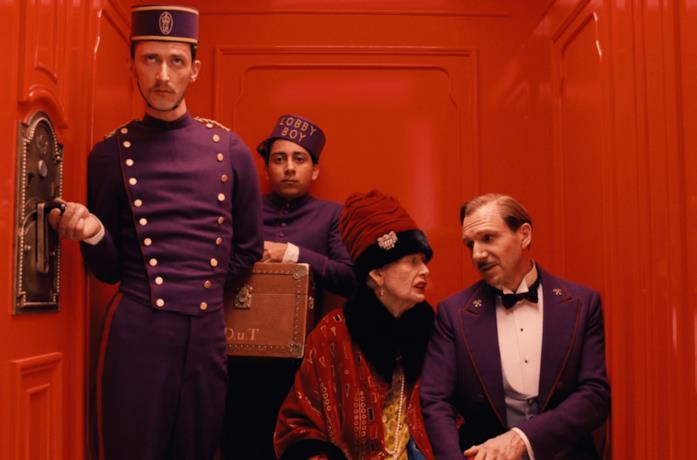 Monsieur Gustave, alcuni dipendenti dell'hotel e una donna usano un ascensore rosso