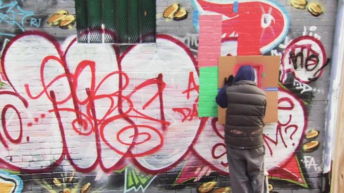 Banksy mentre crea un'opera Un misterioso artista sta disegnando qualcosa in un muro