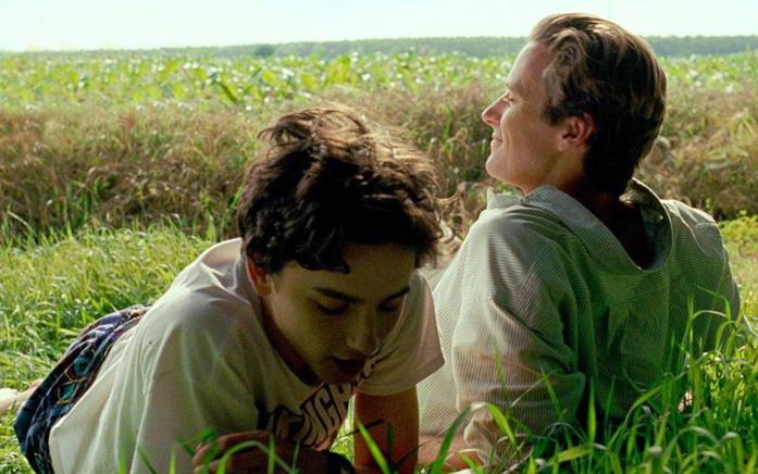 Timothée Chalamet ed Armie Hammer stesi sull'erba in una scena del film