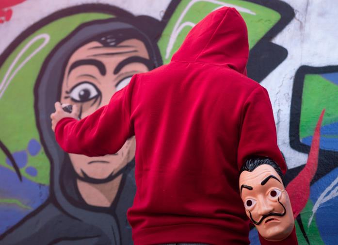Ragazzo con felpa rossa dipinge murales a tema La Casa di Carta