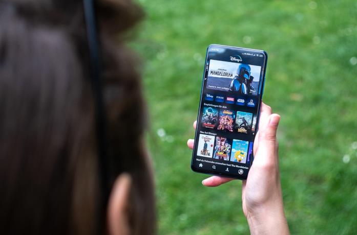 Una ragazza guarda uno smartphone su cui è installata Disney+