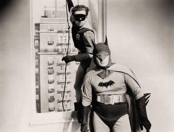 Batman e Robin nel serial cinematografico degli anni '40 Batman in piedi in un appartamento, mentre Robin entra dalla finestra