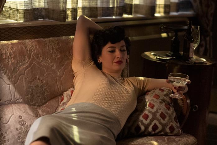 Marielle Heller Alma stesa sul divano con un drink in mano