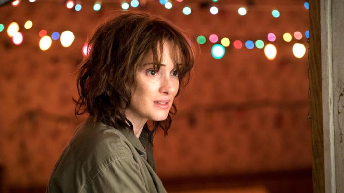 Winona Ryder è Joyce Byers in Stranger Things 1 Wynona Ryder in Stranger Things 1 con lampadine colorate sullo sfondo