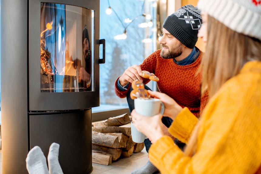Coppia beve un drink vicino a una stufa a legna accesa 