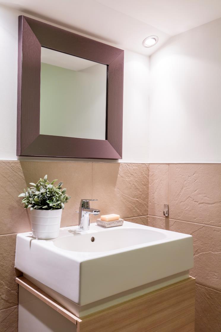 Bagno con piastrelle beige e specchio marrone